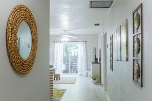 A hallway with a woven mirror, a ceiling fan, and a series of framed fish on the wall. - Gulf Coast Corner Condo Near Charlotte Harbor (Punta Gorda)