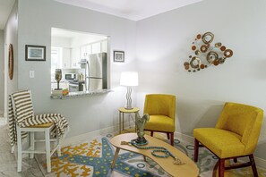 A living room with a sofa, chairs, a coffee table, a lamp, and a decorative wall piece. - Gulf Coast Corner Condo Near Charlotte Harbor (Punta Gorda)