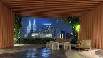 Un espacio de asientos al aire libre con vista a un horizonte urbano nocturno.