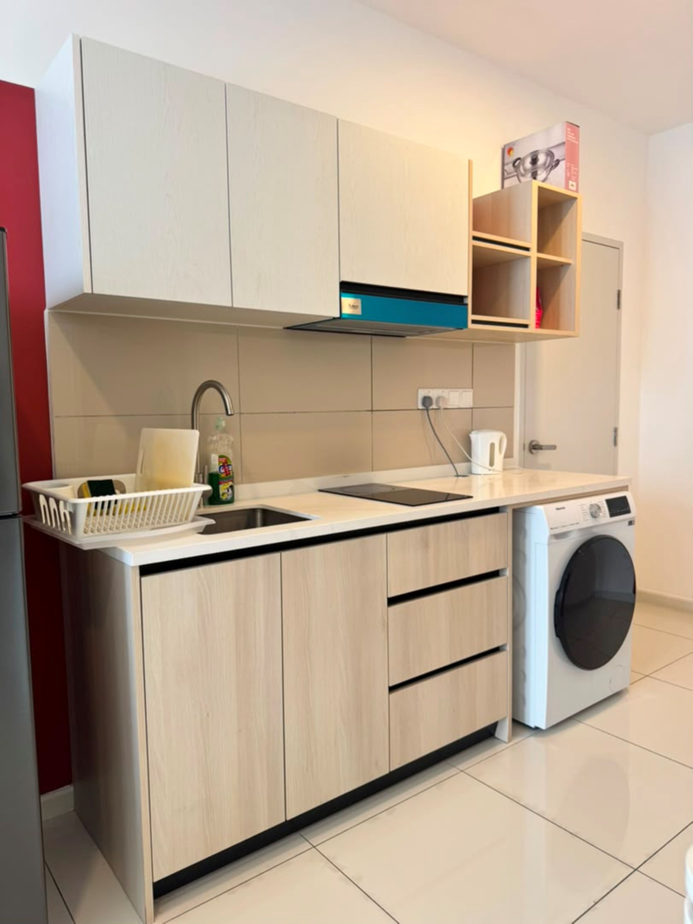 Una cocina moderna con lavadora integrada, un lavamanos y una encimera con una cesta.