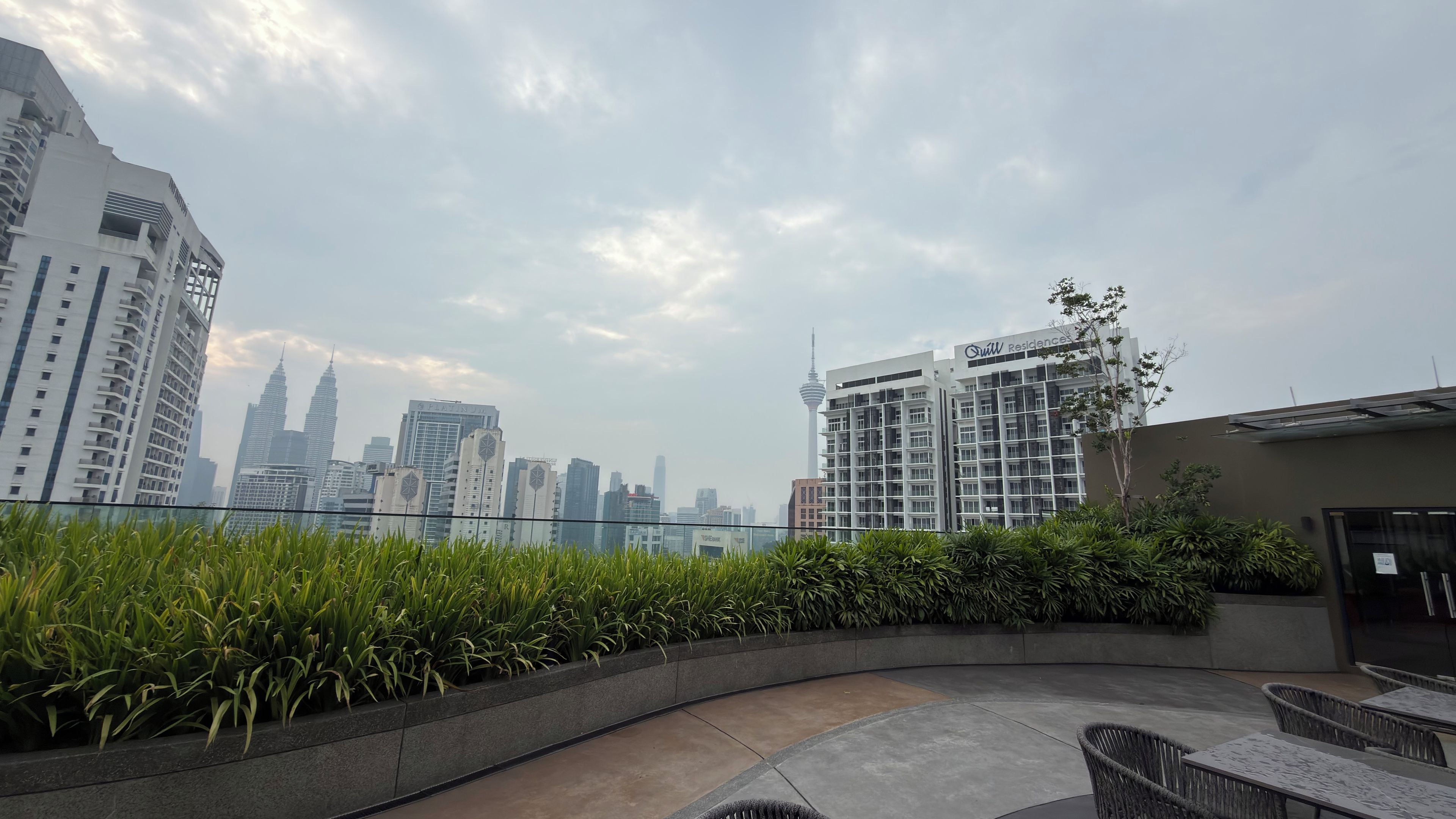 Una terraza en la azotea con vistas al horizonte de la ciudad, que incluye una torre destacada y edificios residenciales.