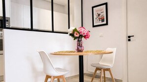 Un'area pranzo moderna con un tavolo rotondo, due sedie bianche e un vaso con fiori.