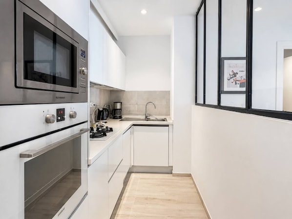 A modern kitchen with stainless steel appliances, a built-in oven, and a sink. - Luxury apartment, one bedroom, prestigious residence (Marsa)