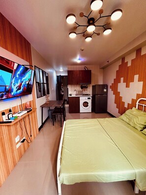 A room with a bed, a television, a kitchen area, and a dining table. - Pool-view near airport  Saekyung Village Phase 3 (Lapu-Lapu)