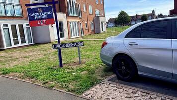 Een woonwijk met een bordje voor Shortland Horne Let, een witte auto geparkeerd aan de straat, en een bord met de straatnaam Elder Court.