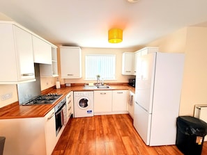 A compact kitchen with white cabinets, a stove, a washing machine, and a refrigerator. - Bright & Cosy 1-Bed flat with Free Parking (West Midlands)
