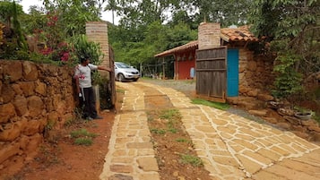 A stone pathway leading to a rustic building with a blue door, surrounded by greenery.