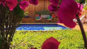 A pool area with a wooden deck and lounge chairs.