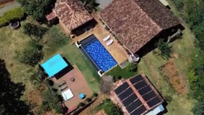 Een woonhuis met een zwembad, zonnepanelen en een omheinde tuin.