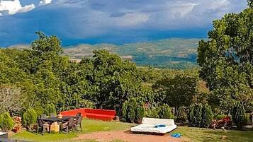 Piscina com vista para um edifício de telhados vermelhos e vegetação exuberante ao fundo.