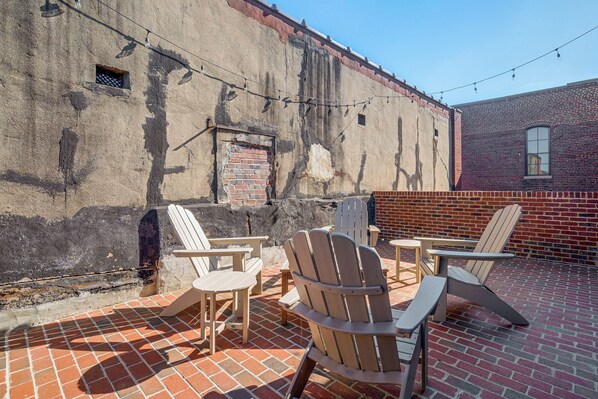 Un patio con mobiliario exterior y pared de ladrillo.