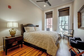 A bedroom with a bed, a nightstand, a lamp, a window, and a chair.