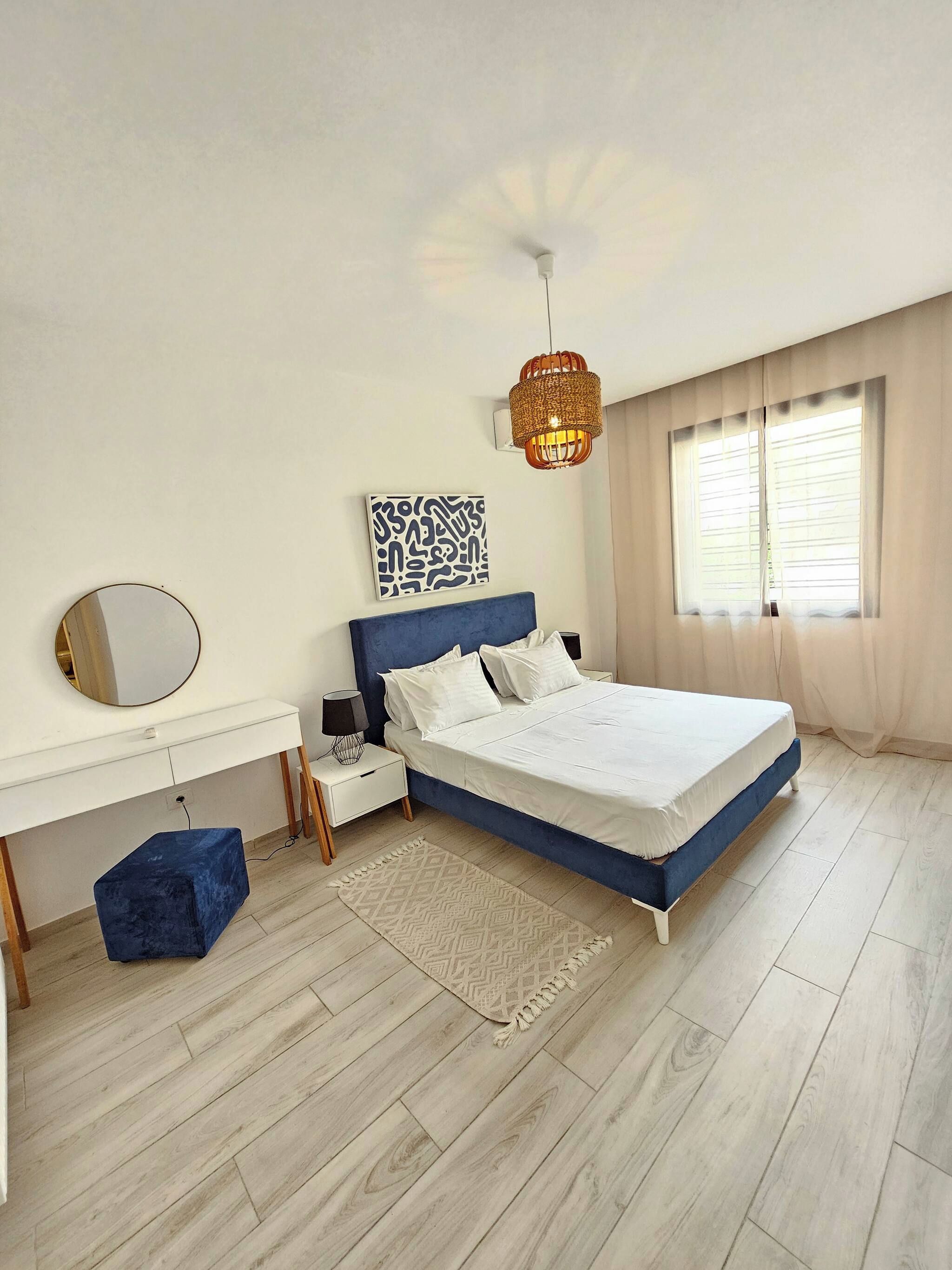 A bedroom with a bed, bedside tables, a mirror, a rug, and a window with curtains.