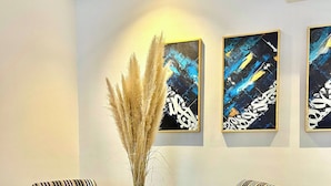Zona pranzo con tavolo rotondo, sedie a righe e arte astratta alle pareti.