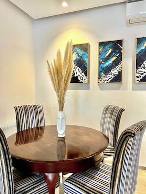 A dining area with a round table, striped chairs, and abstract wall art. - Contemporary Haven in the Heart of La Marsa (Marsa)