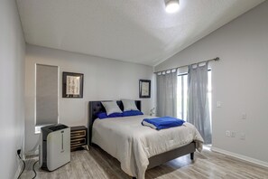 Ein Schlafzimmer mit einem Bett, einem Heizkörper, einem Fenster mit Vorhängen und einer Wandsteckdose.