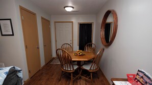 Un coin repas avec une table et des chaises en bois, un miroir au mur et un panneau d’accueil posé sur la table.