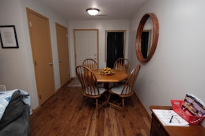 Uma área de refeições com mesa e cadeiras de madeira, um espelho na parede e uma placa de boas-vindas sobre uma mesa.
