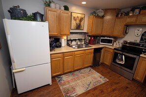 A kitchen with wooden cabinets, a refrigerator, a microwave, a stove, and a coffee maker.