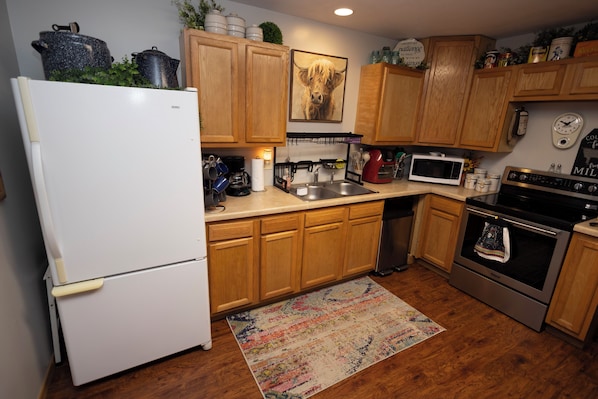A kitchen with wooden cabinets, a refrigerator, a microwave, a stove, and a coffee maker.