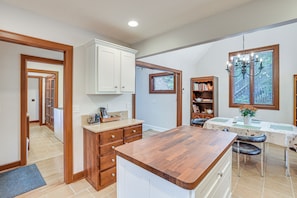 A kitchen with wooden cabinets, a dining area with a table and chairs, and a window with blinds. - Chattanooga Home w/ Treetop Deck & Yard! (Chattanooga)