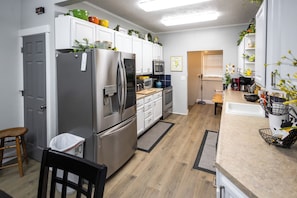 A modern kitchen with stainless steel appliances, white cabinetry, and a wooden floor.