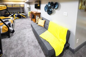 A room with bunk beds, a sofa, and a television.