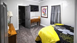 Une chambre à coucher comprenant un lit, une commode, un bureau, un téléviseur et un placard.