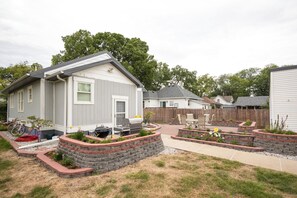 A residential area with houses, a barbecue grill, and a garden with raised flower beds.