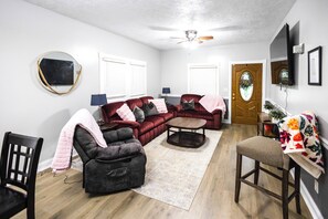 A living room with a sectional sofa, a loveseat, a coffee table, and a dining area with a chair and table.