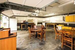 A spacious garage with a dining area, kitchen cabinets, and a ceiling fan.