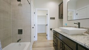 Un baño moderno con bañera, lavamanos amplio y espejo.