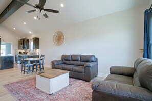 Ein modernes Wohnzimmer mit einem grauen Sofa, einem weißen Couchtisch und einem gemusterten Teppich.