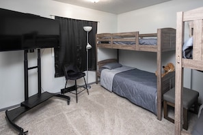 Habitación pequeña con literas, escritorio, silla y televisor.