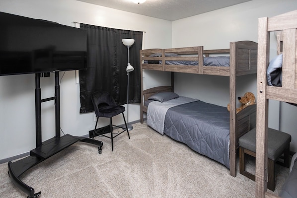 A compact room with bunk beds, a desk, a chair, and a TV.