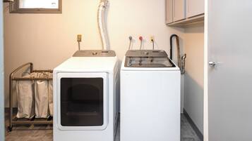 A laundry room with two front-loading washing machines and a drying rack.