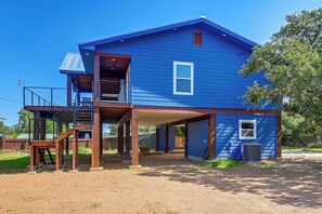 Ein zweistöckiges blaues Haus mit überdachter Veranda und einem kleinen Balkon.