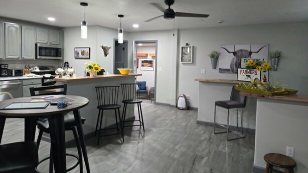 A modern kitchen with a microwave, stove, and dining area with chairs and a table. - 'Honey Bee' Family Home in Columbus, Nebraska! (Columbus)