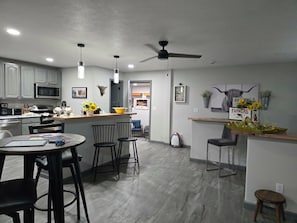 A modern kitchen with a microwave, stove, and dining area with chairs and a table.
