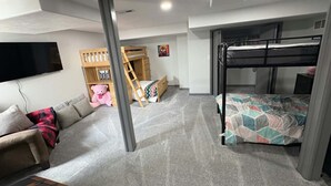 A bedroom with bunk beds, a sofa, a TV, and a wooden playhouse. - 'Honey Bee' Family Home in Columbus, Nebraska! (Columbus)
