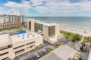 Ein Küstenhotel mit mehreren Gebäuden, einem Parkplatz und einem Strand im Hintergrund.
