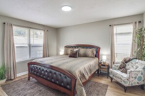 Ein Schlafzimmer mit einem großen Bett, Nachttischlampen, einem Sessel und einer Topfpflanze.
