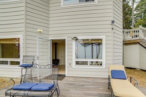 A house with a covered patio, a sliding glass door, a small outdoor seating area with a chair and a table, and a visible chimney.