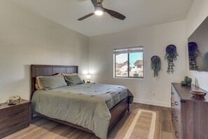 A bedroom with a bed, bedside tables, a ceiling fan, a window, and a view of the outside. - Mtn Views, Hot Tub! Extended Lake Havasu Escape (Lake Havasu City)