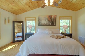 Ein Schlafzimmer mit einem großen Bett, zwei Nachttischlampen, einem Deckenventilator und einem Gemälde an der Wand.