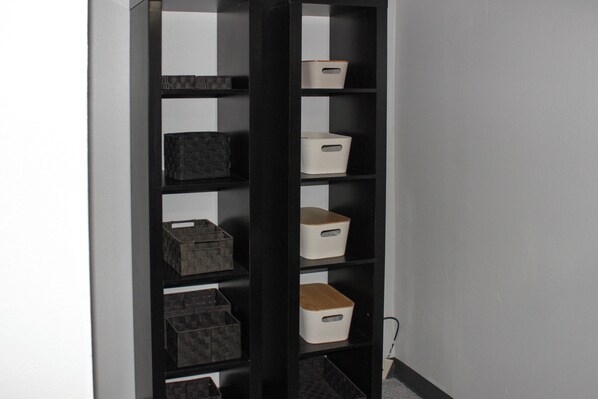 A black shelving unit with multiple storage bins against a wall.