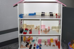 A dollhouse with multiple rooms, including a kitchen, living room, and bedrooms.