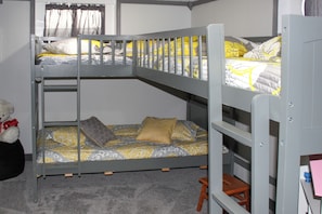 A bunk bed with a lower bunk and a higher bunk, both with patterned bedding.