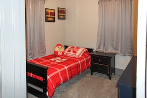 Quarto com cama, mesa de cabeceira, cômoda e duas pinturas na parede.