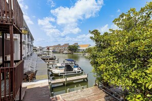 A marina with docked boats, wooden walkways, and buildings in the background. - Bayside Waterfront OC Sleeps 8 | Beach | Boardwalk (Ocean City)
